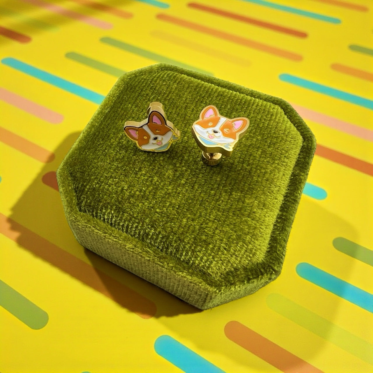 Corgi-shaped earrings in a green box on a colorful background
